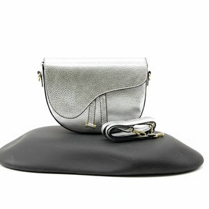Silver handbag with a strap on a black stand against a white background